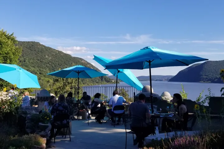 a group of people sitting at a table with a blue umbrella