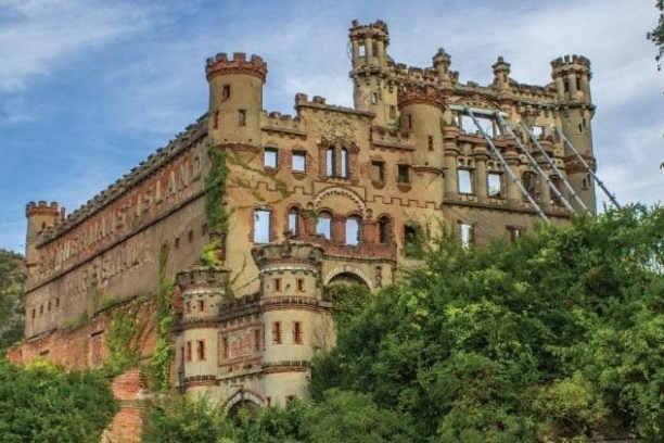 Historic brick castle ruin with towers, surrounded by trees.