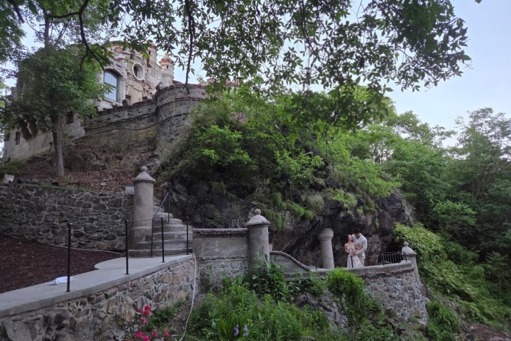 Historic stone building on a lush hillside with winding pathways.